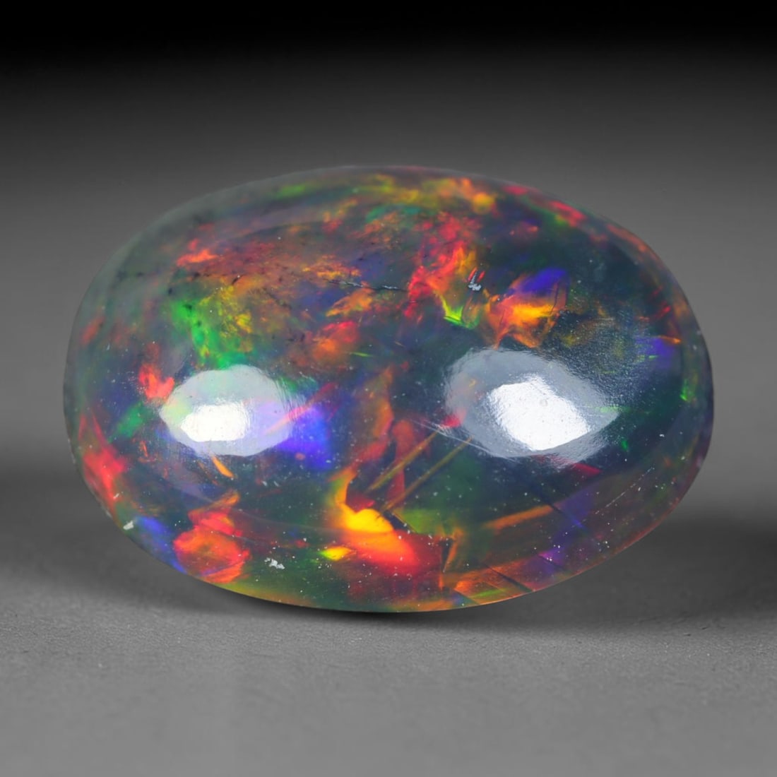 2.07ct Natural Ethiopian Welo Black Smoked Opal Cabochon Loose Gemstone, 84AK: This fully polished Ethiopian Welo opal features a dark smoked base with vivid, sweeping play-of-color shifting across its glossy dome surface, measured at 11.2x8.3x4.5mm. The black smoke treatment de