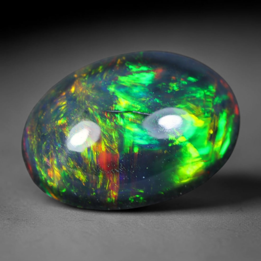 2.00ct Natural Ethiopian Welo Black Smoked Opal Cabochon Loose Gemstone, 67AK: This fully polished Ethiopian Welo opal features a dark smoked base with vivid, sweeping play-of-color shifting across its glossy dome surface, measured at 11.2x8.3x4.6mm. The black smoke treatment de