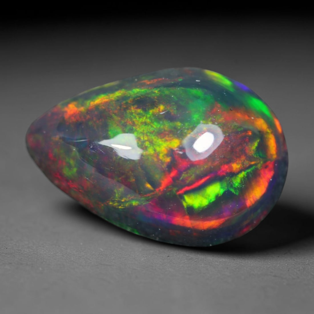 1.68ct Natural Ethiopian Welo Black Smoked Opal Cabochon Loose Gemstone, 58AK: This fully polished Ethiopian Welo opal features a dark smoked base with vivid, sweeping play-of-color shifting across its glossy dome surface, measured at 11x7.5x4.6mm. The black smoke treatment deep