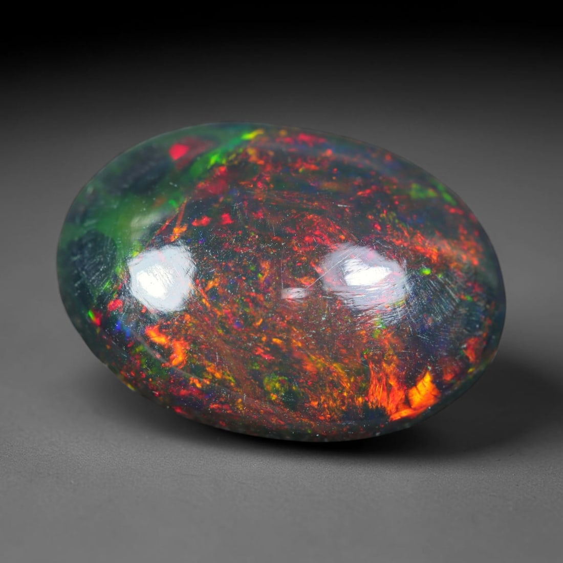 3.17ct Natural Ethiopian Welo Black Smoked Opal Cabochon Loose Gemstone, 31FL: This fully polished Ethiopian Welo opal features a dark smoked base with vivid, sweeping play-of-color shifting across its glossy dome surface, measured at 13.7x10x4.5mm. The black smoke treatment dee