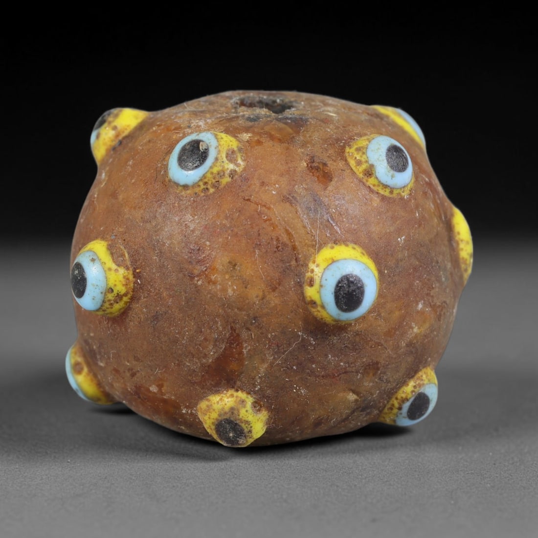 Ancient Canaanite & Phoenician Cultures Multi-Eye Applique Round Glass Bead (3000-300 BCE), 31AE: This antique multi-eye round glass bead originates from Canaanite & Phoenician Cultures, the Levantine seafaring civilization renowned for crafting apotropaic eye glass talismans circulated across Med