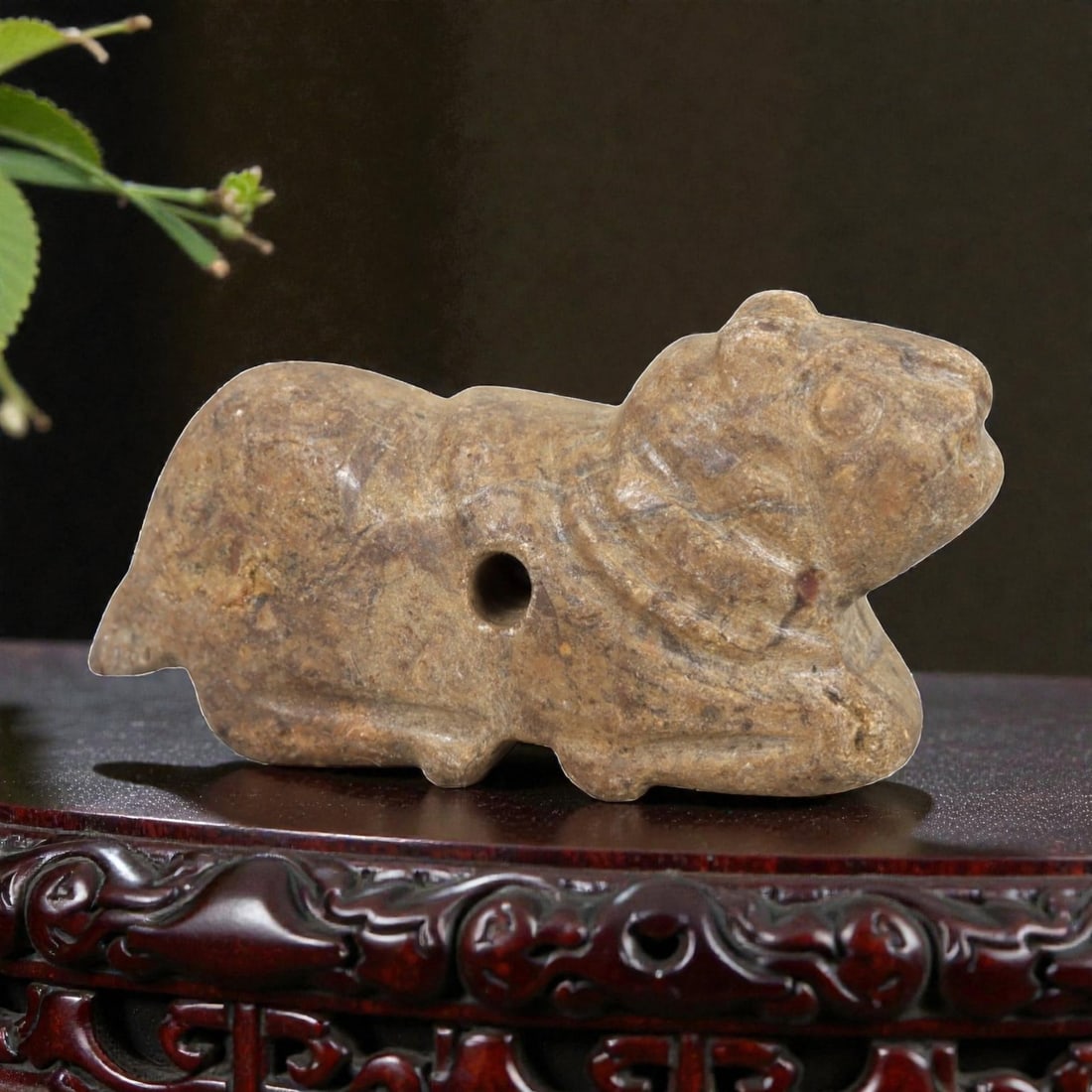 Ancient Stone Zoomorphic Amulet - Near Eastern Animal Figure, 55AM: This amulet is carved from speckled stone, depicting a stylized quadrupedal animal in a crouched, forward-leaning posture, with subtle incised lines defining the neck and facial features. The piece re
