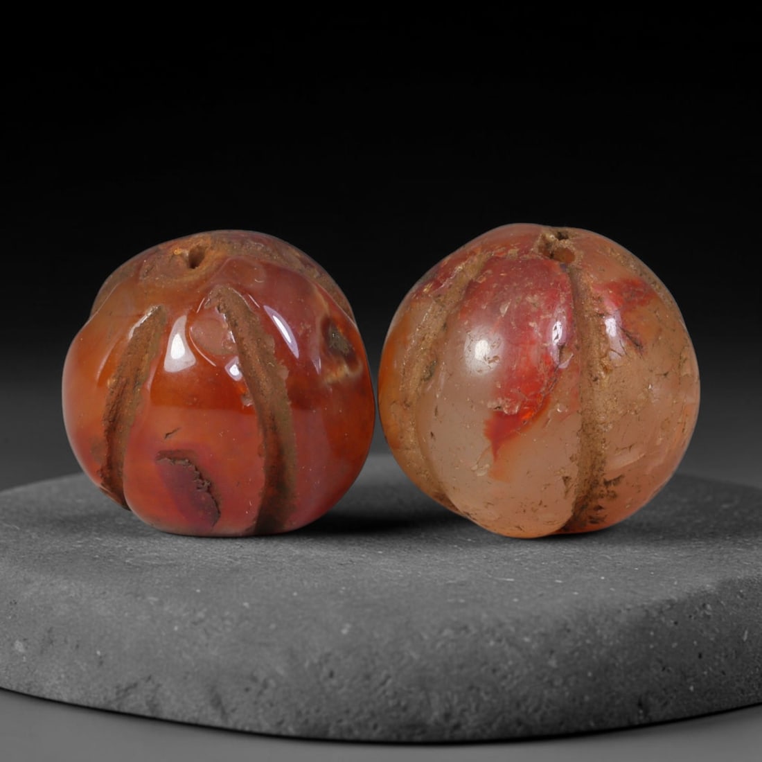 Ancient Medieval Khmer Angkor Culture Carved Carnelian Melon Bead Pair (802-1431 CE), 45AE: This matched pair of antique hand-carved melon form carnelian beads originates from Khmer Angkor Culture, the medieval Southeast Asian civilization renowned for crafting ritual chalcedony adornments f