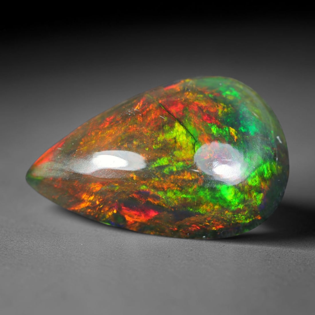 2.50ct Natural Ethiopian Welo Black Smoked Opal Cabochon Loose Gemstone, 76AK: This fully polished Ethiopian Welo opal features a dark smoked base with vivid, sweeping play-of-color shifting across its glossy dome surface, measured at 13.3x8.6x4.7mm. The black smoke treatment de