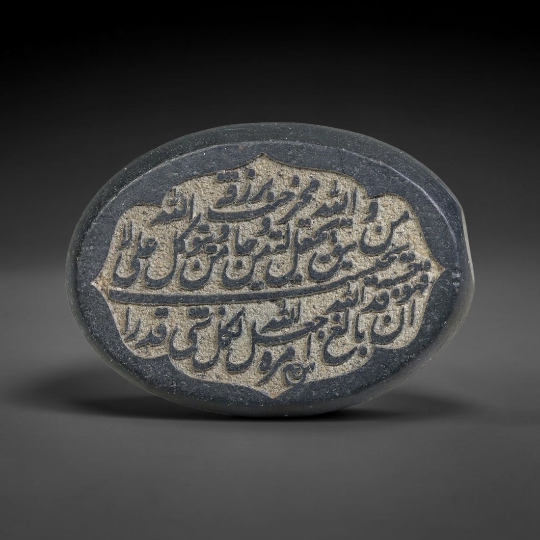An Islamic Natural Green Stone Circular Script Engraved Talisman Tablet, 29FG: This polished green stone talisman tablet with elaborate concentric layered script engraving covering the central face, framed within a stylized petal-shaped inner border. Fine recessed engraved detai