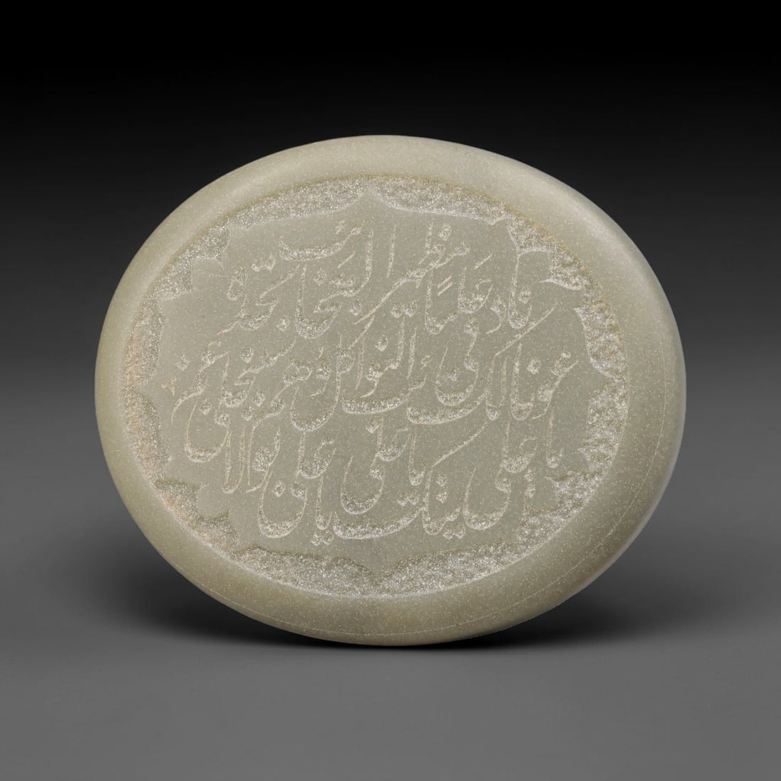 An Islamic Natural Green Stone Circular Script Engraved Talisman Tablet, 27FG: This polished green stone talisman tablet with elaborate concentric layered script engraving covering the central face, framed within a stylized petal-shaped inner border. Fine recessed engraved detai