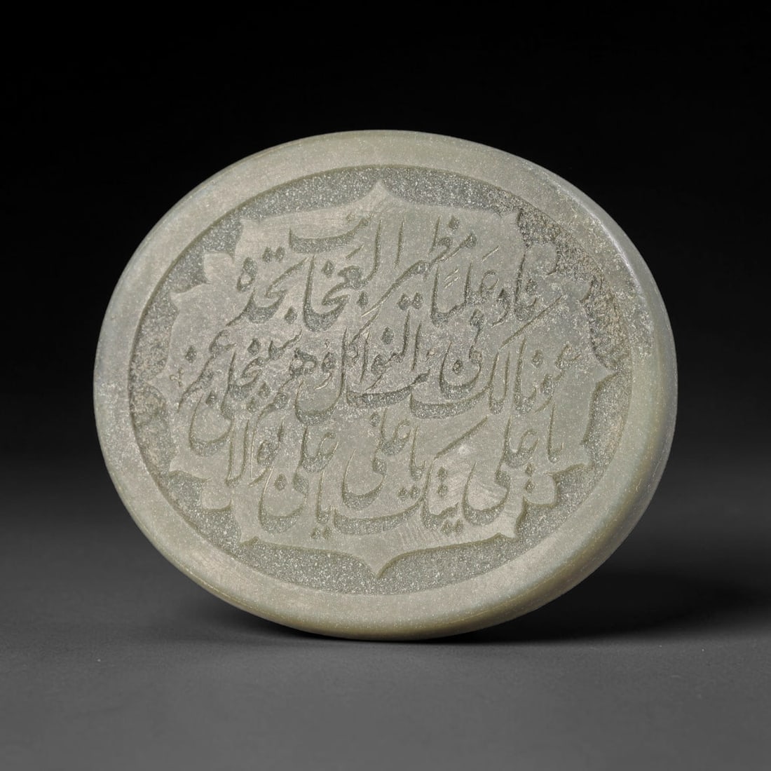 An Islamic Natural Green Stone Circular Script Engraved Talisman Tablet, 38FG: This polished green stone talisman tablet with elaborate concentric layered script engraving covering the central face, framed within a stylized petal-shaped inner border. Fine recessed engraved detai