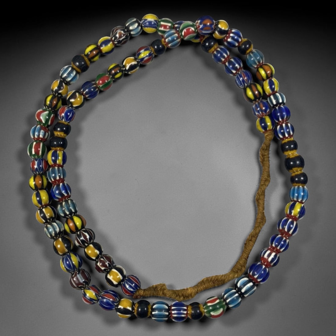 Strand of Antique Chevron Glass Beads, Unstrung, 52AH, 52AH: A single strand of unstrung antique chevron glass beads, measuring approximately 30 cm in length. The strand features round beads adorned with vibrant, multicolored striped chevron patterns, character
