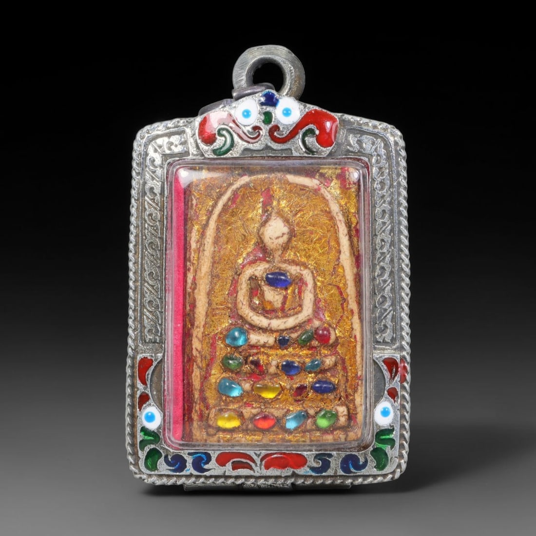 Thai Buddhist Folk Tradition Enclosed Amulet Pendant with Decorative Metal Casing, 43AH: This Thai sacred amulet is housed within an ornate hinged metal protective casing fitted with a top loop for wear as a pendant. The casing features intricate embossed surface detailing and a continuou