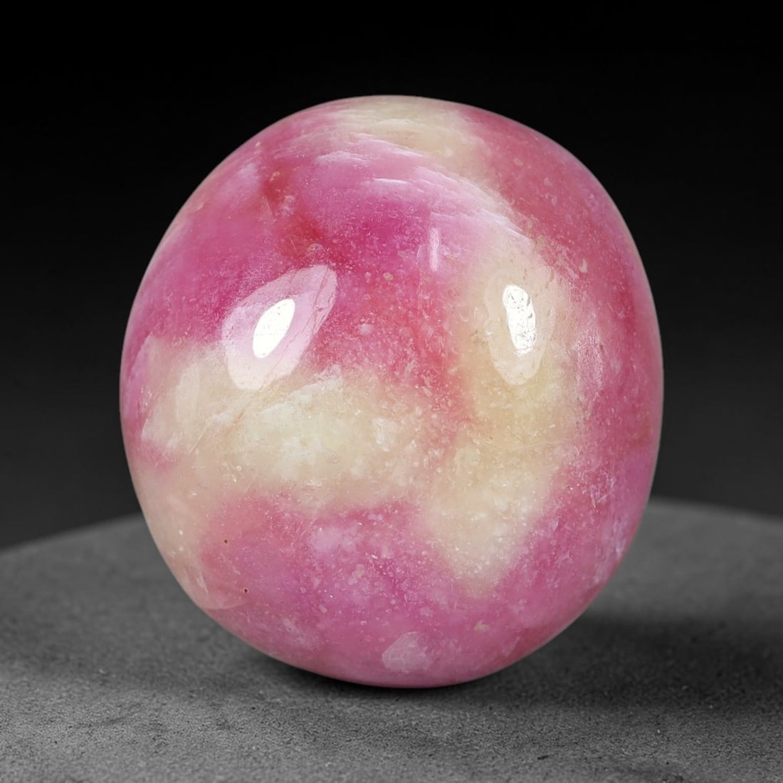 26.78 Carats Natural Mozambique Bicolor Ruby Loose Gemstone, 50FG: This natural Mozambique bicolor ruby cabochon holds dimension measurements of 17.4x16x8.8mm, displaying soft swirled intermix of rich pink and pale creamy mineral tones that blend seamlessly across th