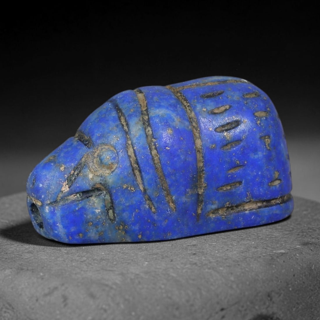 Ancient Egyptian Lapis Lazuli Hippopotamus Amulet (664-30 BCE), 37AB: Hand-carved vivid blue lapis lazuli hippopotamus protective amulet, detailed with incised linear motifs marking facial features and body segmentation. Faint golden pyrite flecks scatter across the sto