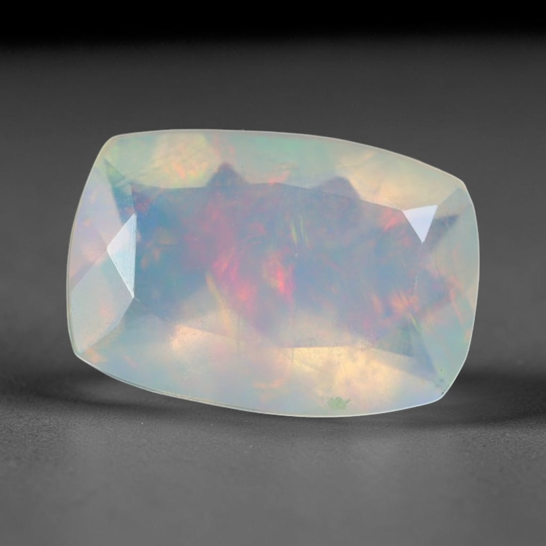 1.45ct Natural Ethiopian Welo Faceted Opal, 7EB: This expertly faceted finished opal holds soft shifting internal light phenomena visible across polished reflective planes within its 10x6.8x4.6mm calibrated measurements, precise faceting structure m