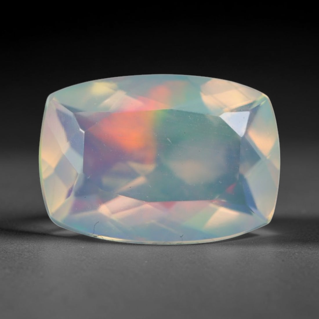 1.16ct Natural Ethiopian Welo Faceted Opal, 9EB: This expertly faceted finished opal holds soft shifting internal light phenomena visible across polished reflective planes within its 9.1x6.4x4.2mm calibrated measurements, precise faceting structure 