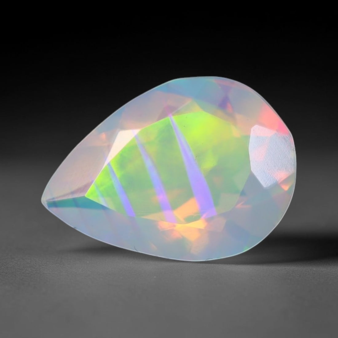 0.94ct Natural Ethiopian Welo Faceted Opal, 2EB: This expertly faceted finished opal holds soft shifting internal light phenomena visible across polished reflective planes within its 9.2x6.6x4.6mm calibrated measurements, precise faceting structure 