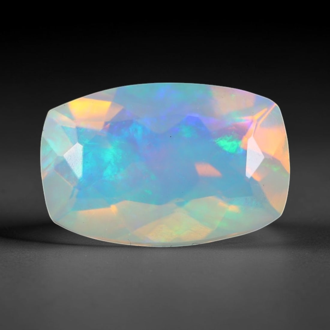 1.24ct Natural Ethiopian Welo Faceted Opal, 1EB: This expertly faceted finished opal holds soft shifting internal light phenomena visible across polished reflective planes within its 10.2x6x4.8mm calibrated measurements, precise faceting structure m