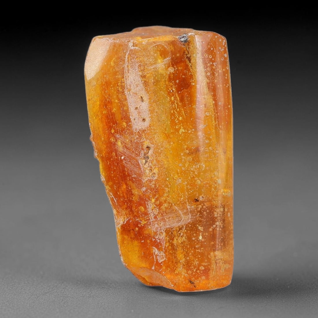 16.52ct Natural Baltic Polished Loose Freeform Amber Gemstone, 99AT: This smoothly polished freeform amber piece carries warm translucent organic clarity with fine natural fossil flecks and tiny mineral inclusions suspended throughout its 26x15mm flowing unstructured s