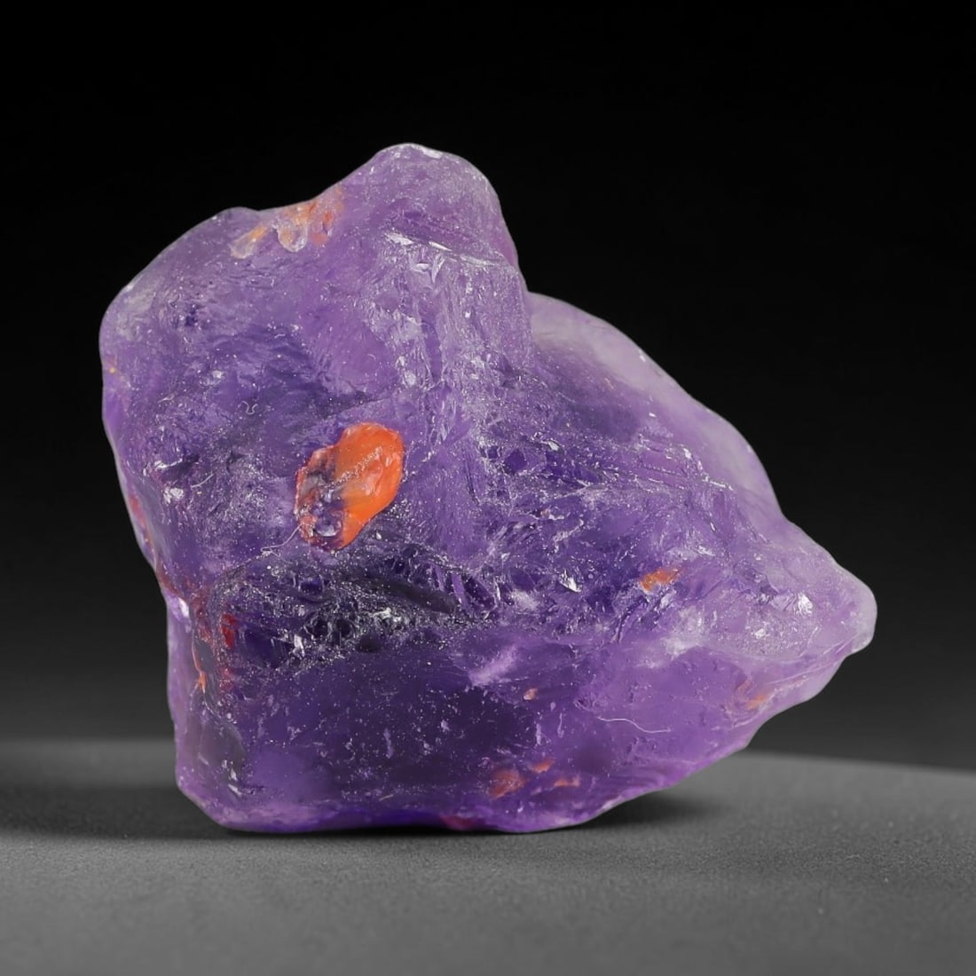 133ct Natural Chinese Deep Violet Purple Fluorite Rough, 3AT: This rugged fluorite rough boasts rich layered violet purple saturation blended with warm rust-colored mineral inclusions that streak its uneven raw surface, soft translucency lets light drift through