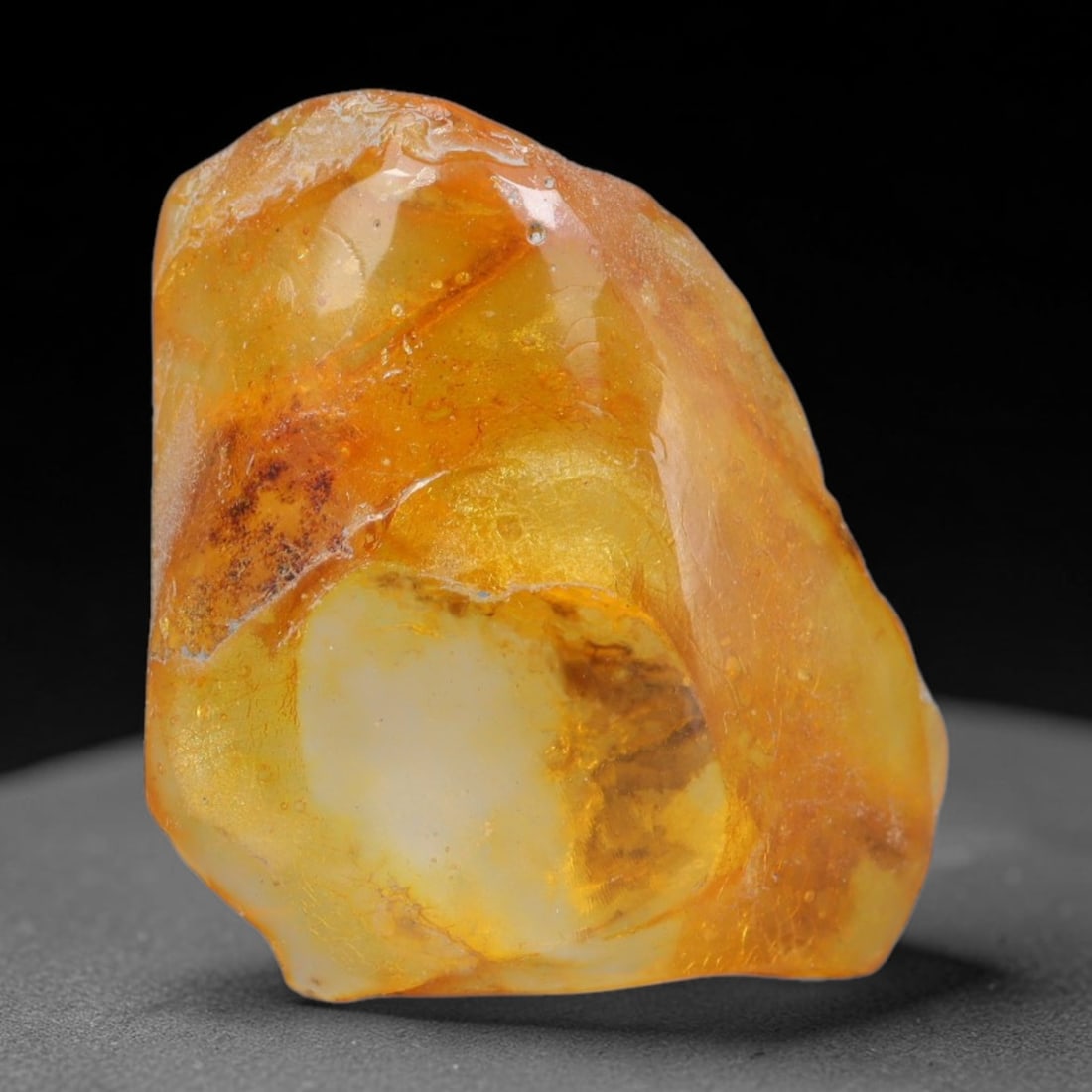 14.62ct Natural Baltic Polished Loose Freeform Amber Gemstone, 43AT: This smoothly polished freeform amber piece carries warm translucent organic clarity with fine natural fossil flecks and tiny mineral inclusions suspended throughout its 26x24mm flowing unstructured s