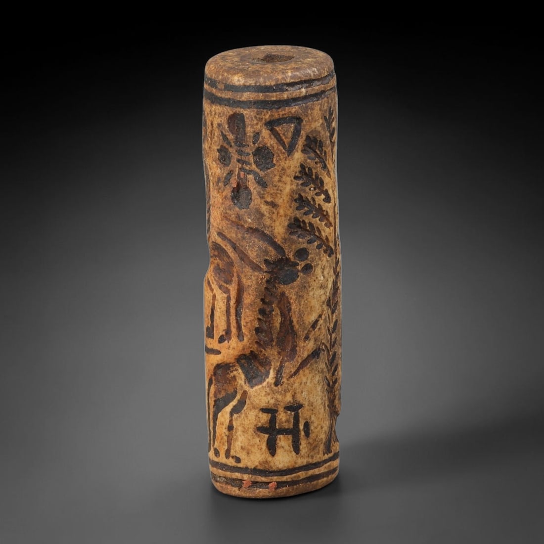 Ancient Mesopotamian Cream Stone Zoomorphic Cylinder Seal (2900-2334 BCE), 84AB: Barrel-form pale mineral stone cylinder seal with full central longitudinal bore for cord suspension. Exterior surface finely incised with detailed figural scenes featuring horned antelope fauna, styl