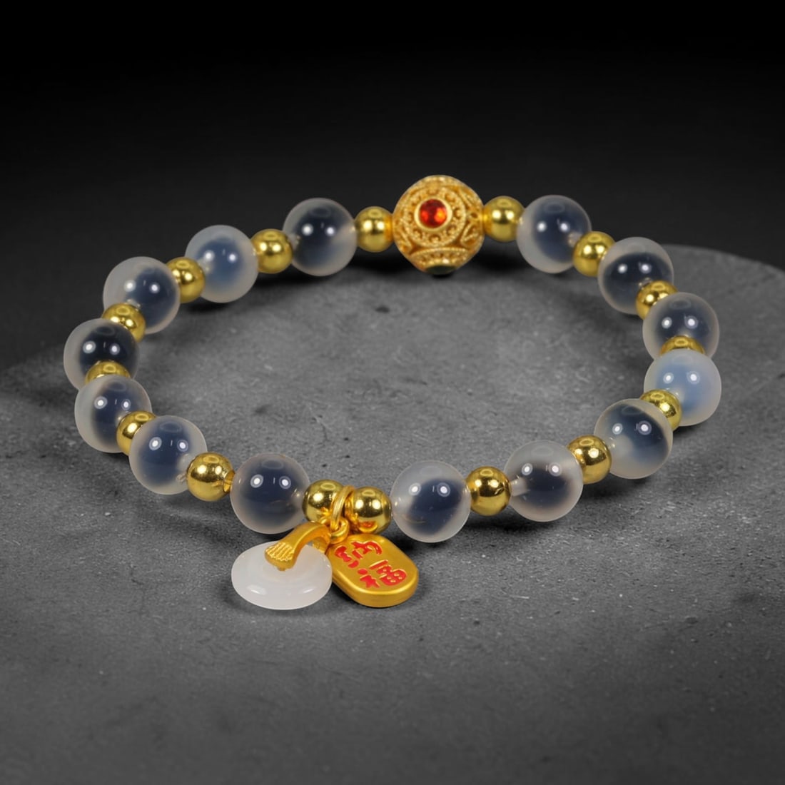 A Chinese Glass Beaded Bracelet - Frosted Grey Glass Gilded Charm Strand, 8AP: Hand-strung bracelet constructed with smooth 8mm frosted translucent grey glass round beads, separated by polished small gilded metal spacer beads. A central ornate filigree gilded focal bead set with