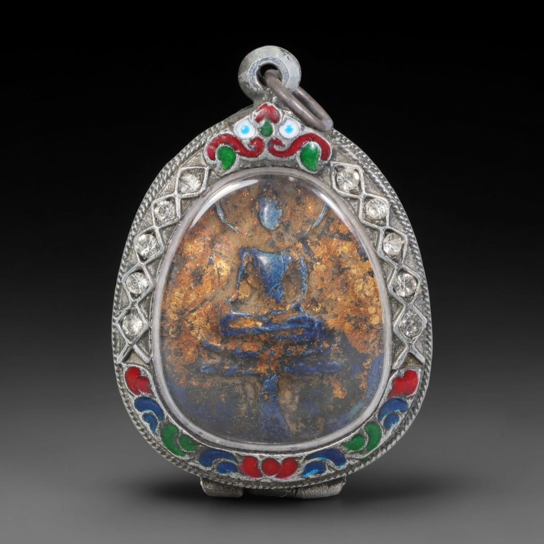 Thai Buddhist Folk Tradition Enclosed Amulet Pendant with Decorative Metal Casing, 22AH: This Thai sacred amulet is housed within an ornate hinged metal protective casing fitted with a top loop for wear as a pendant. The casing features intricate embossed surface detailing and a continuou