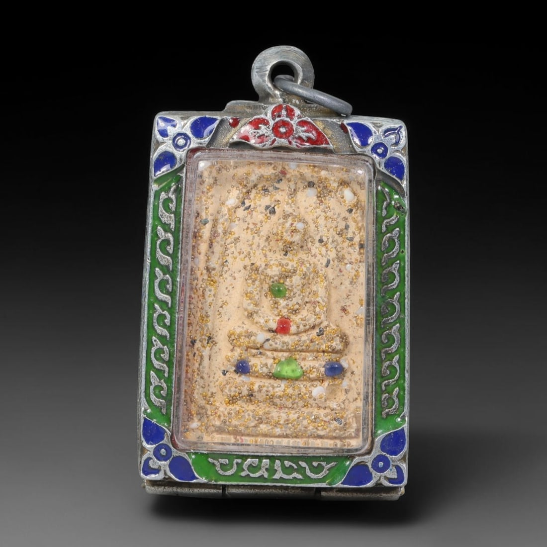 Thai Buddhist Folk Tradition Enclosed Amulet Pendant with Decorative Metal Casing, 15AH: This Thai sacred amulet is housed within an ornate hinged metal protective casing fitted with a top loop for wear as a pendant. The casing features intricate embossed surface detailing and a continuou