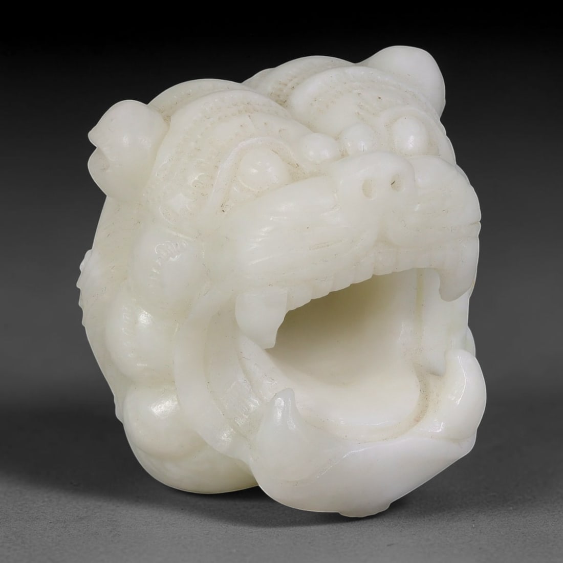 White Nephrite Jade Lion Head - Chinese Carved Figurine, 62AS: Crafted from solid white nephrite jade, this carving displays refined hand chiseling defining the lion's rounded cranial structure, raised circular eyes, flared nostrils, and wide open maw with promin