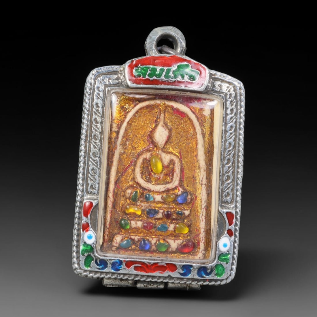 Thai Buddhist Folk Tradition Enclosed Amulet Pendant with Decorative Metal Casing, 23AH: This Thai sacred amulet is housed within an ornate hinged metal protective casing fitted with a top loop for wear as a pendant. The casing features intricate embossed surface detailing and a continuou