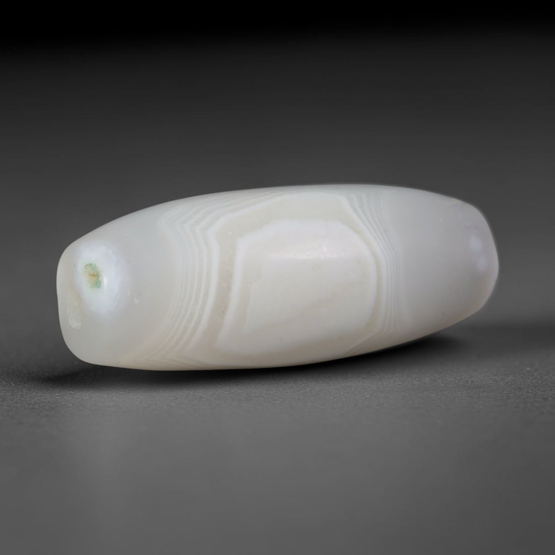 Ancient Satavahana Dynasty White Banded Pale Agate Barrel Bead (230 BCE - 220 CE), 76AD: This lengthy geometric banded agate barrel bead originates from India's Satavahana Dynasty, a prominent South Asian maritime power celebrated for agate talisman production traded across Indian Ocean a