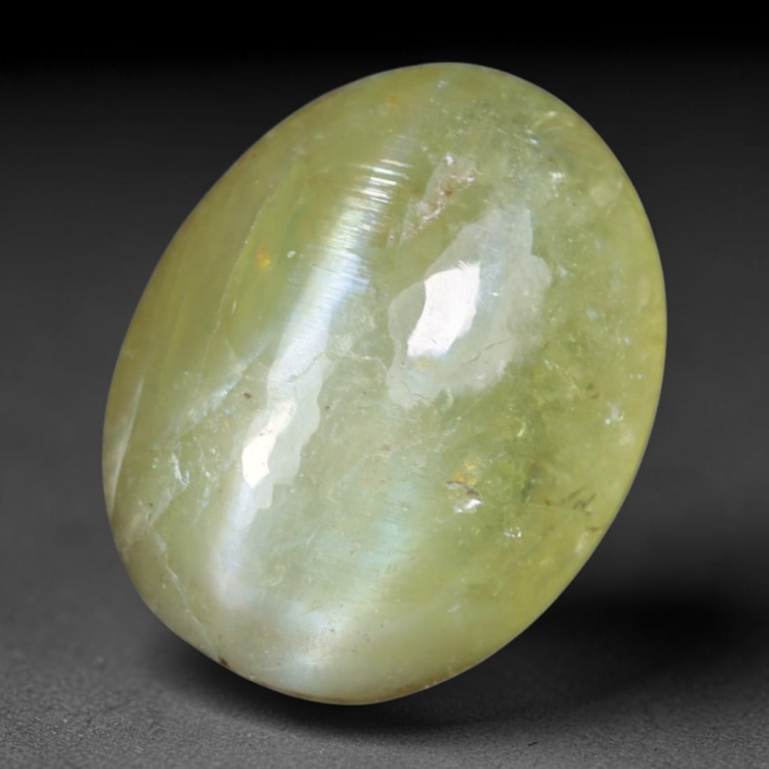 1.49 Carats Natural Ceylon Chrysoberyl Cat's Eye Loose Gemstone, 8AL: This polished Ceylon chrysoberyl cabochon displays a sharp, distinct silvery chatoyant band running across its smooth surface, formed by dense aligned microscopic rutile inclusions inherent to genuine