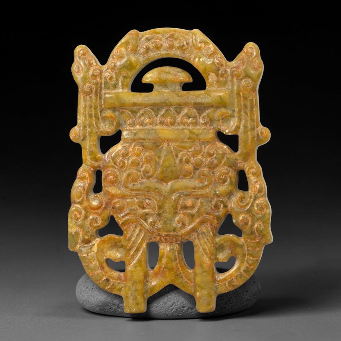 A Chinese Jade Openwork Plaque, 20th Century, 52FC: Carved from mottled jade with olive-green and warm russet tones, the plaque is worked in openwork and low relief to form a symmetrical, vertically oriented composition. The design is dominated by an a