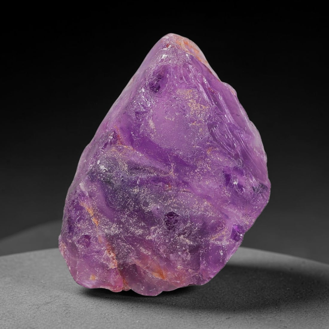 125ct Natural Chinese Deep Violet Purple Fluorite Rough, 10AT: This rugged fluorite rough boasts rich layered violet purple saturation blended with warm rust-colored mineral inclusions that streak its uneven raw surface, soft translucency lets light drift through