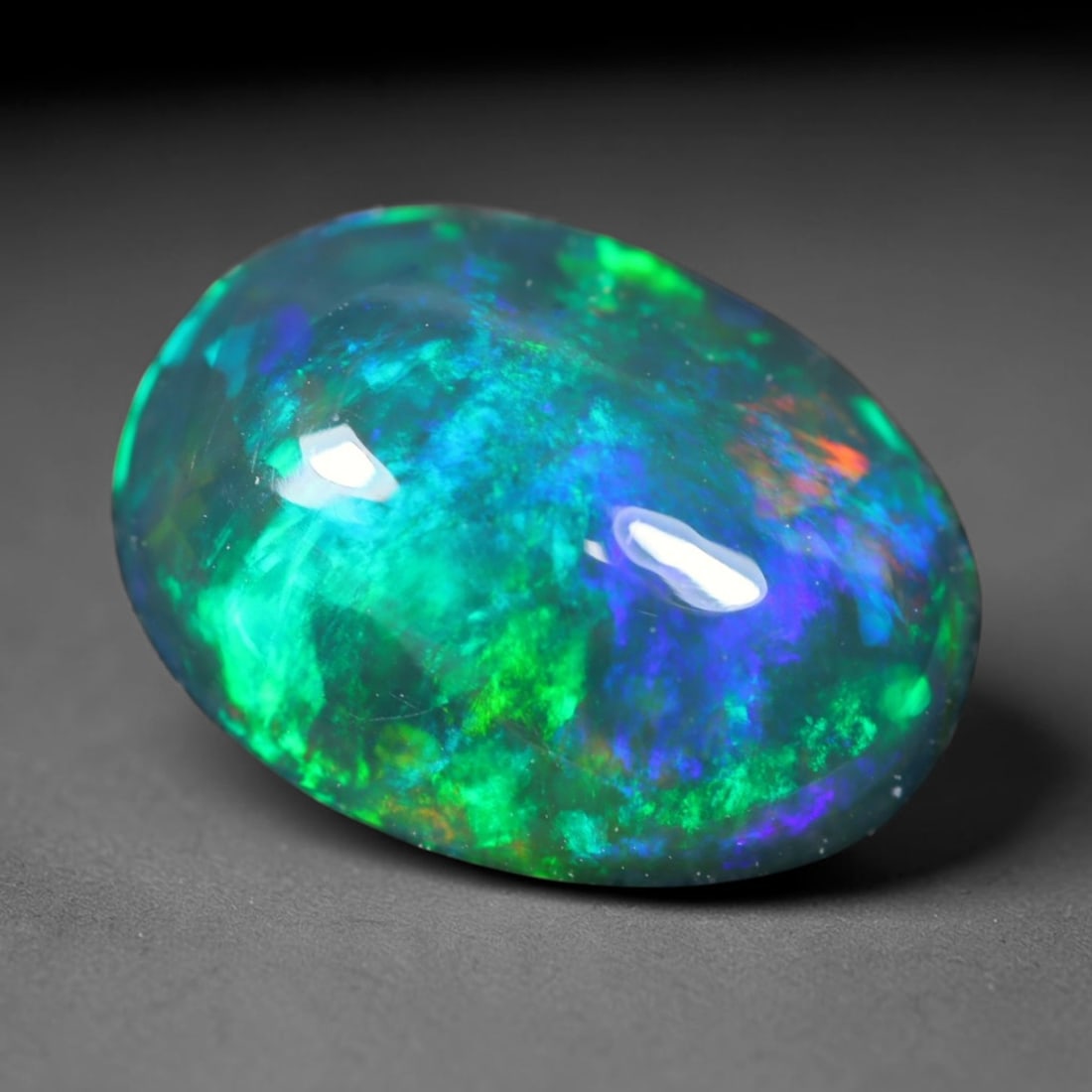 1.38ct Natural Ethiopian Welo Black Smoked Opal Cabochon Loose Gemstone, 44FL: This fully polished Ethiopian Welo opal features a dark smoked base with vivid, sweeping play-of-color shifting across its glossy dome surface, measured at 10x7.7x4mm. The black smoke treatment deepen