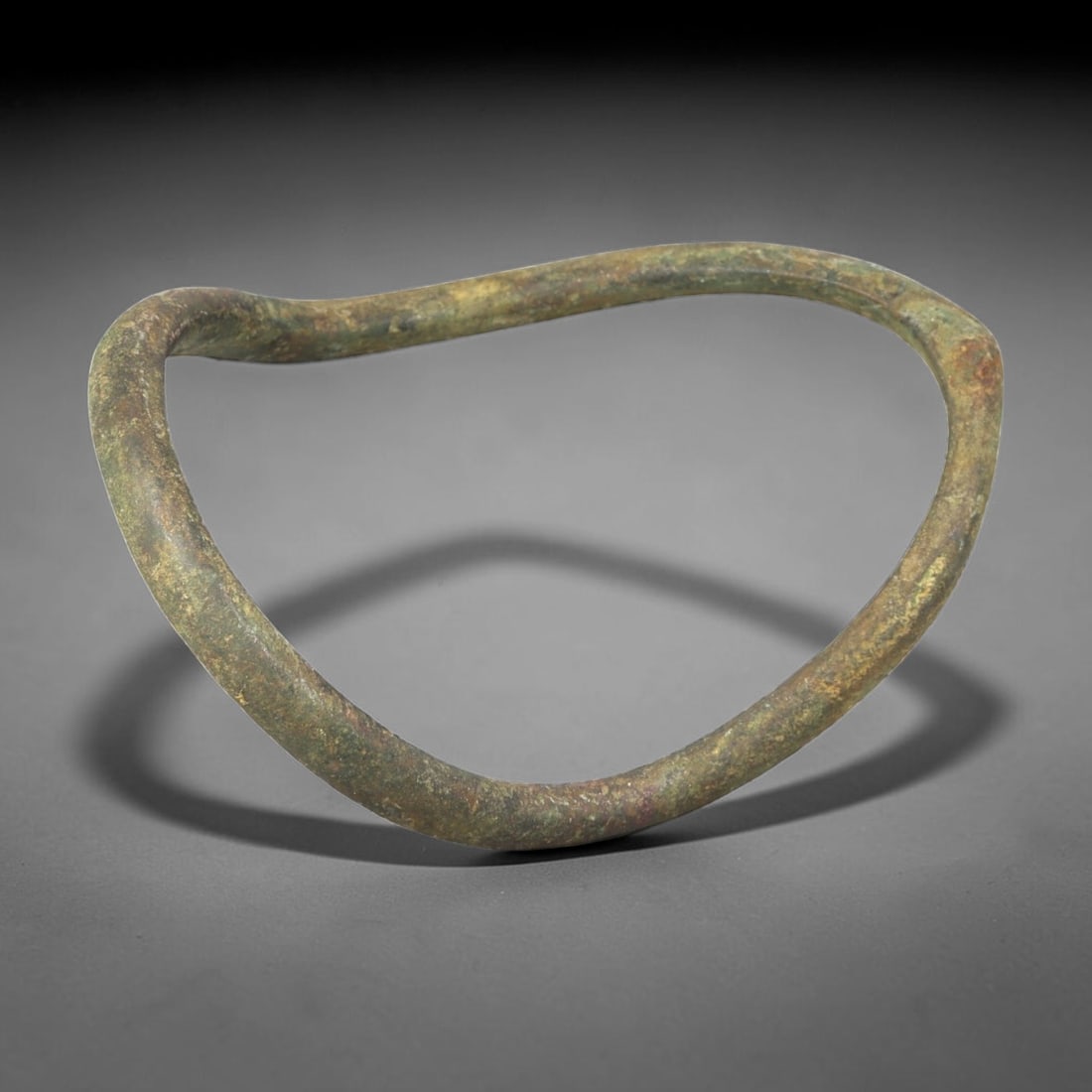 Ancient Bronze Anklet - Roman Penannular Bangle, 29BN: A penannular bronze anklet of ancient Roman origin, formed from a thick, rounded bronze band. The piece has no visible closure mechanism, indicating it was likely worn as a slip-on anklet. The surface