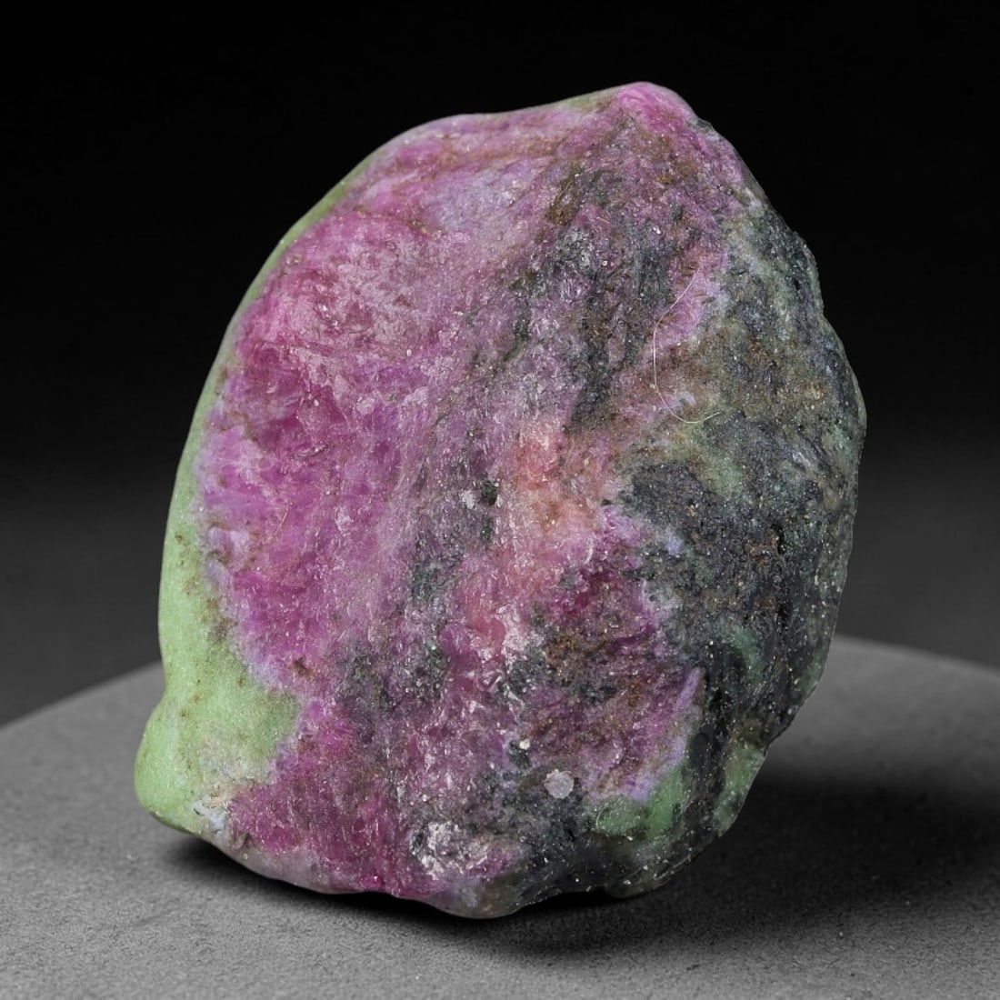 130ct Natural Tanzanian Ruby Zoisite Raw Rough Specimen Mineral Stone, 98FB: This unpolished mineral rough is natural ruby zoisite sourced from Tanzania, exhibiting distinct banded mineral segregation of vibrant green zoisite, magenta ruby crystals, and dark hornblende inclusi