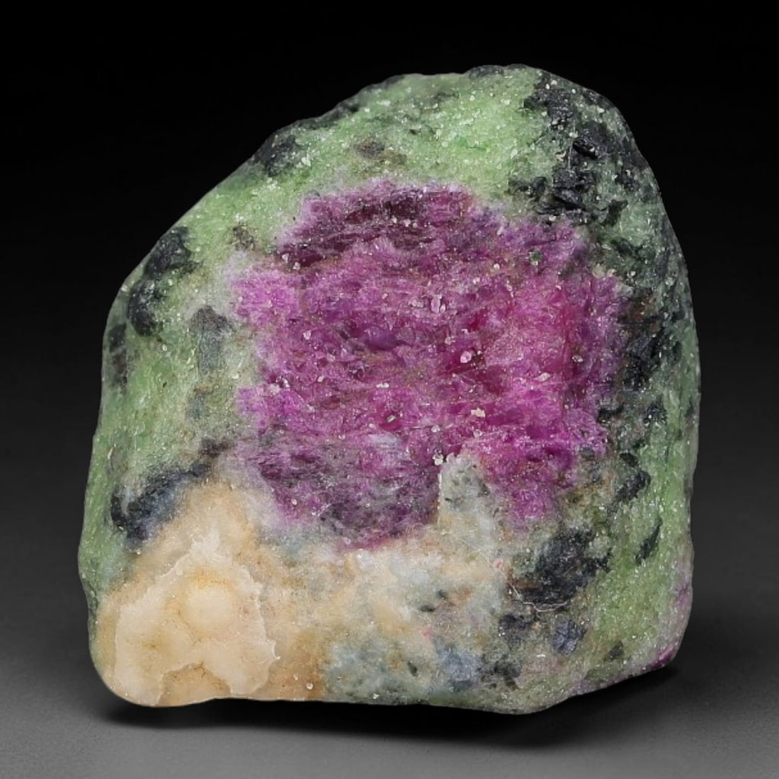 59ct Natural Tanzanian Ruby Zoisite Raw Rough Specimen Mineral Stone, 25FC: This unpolished mineral rough is natural ruby zoisite sourced from Tanzania, exhibiting distinct banded mineral segregation of vibrant green zoisite, magenta ruby crystals, and dark hornblende inclusi