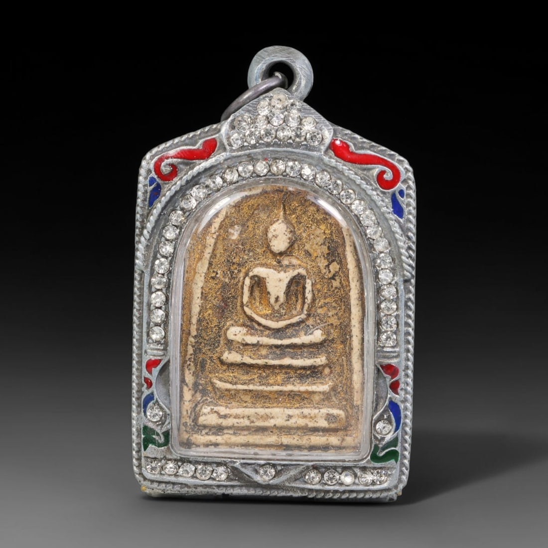 Thai Buddhist Folk Tradition Enclosed Amulet Pendant with Decorative Metal Casing, 21AH: This Thai sacred amulet is housed within an ornate hinged metal protective casing fitted with a top loop for wear as a pendant. The casing features intricate embossed surface detailing and a continuou