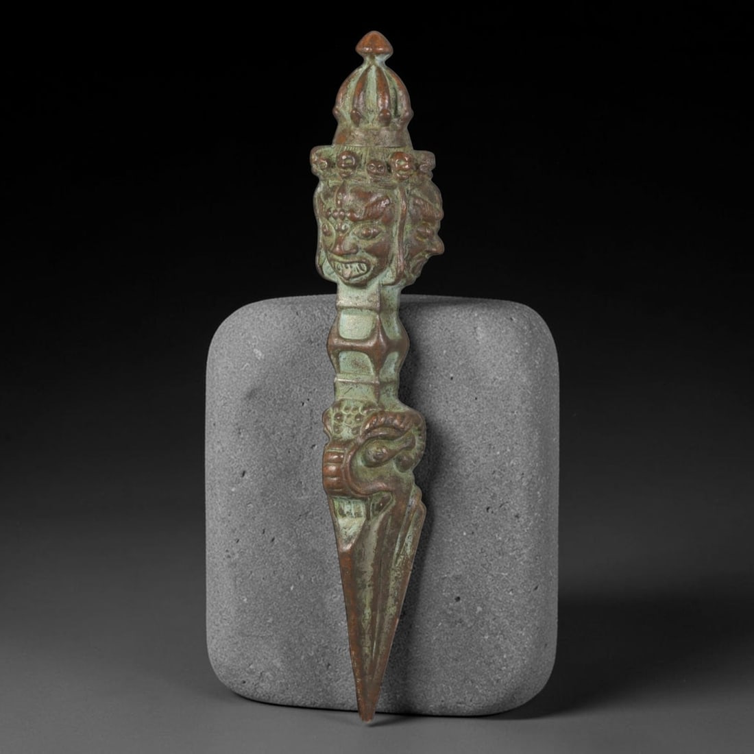 Vintage Tibetan Copper Alloy Multi-Headed Ritual Phurba Dagger, 53AH: Cast copper alloy ceremonial phurba dagger covered in elaborate relief carving along its full vertical length. The top features a tiered crown finial above a section of multi-faced guardian heads rend