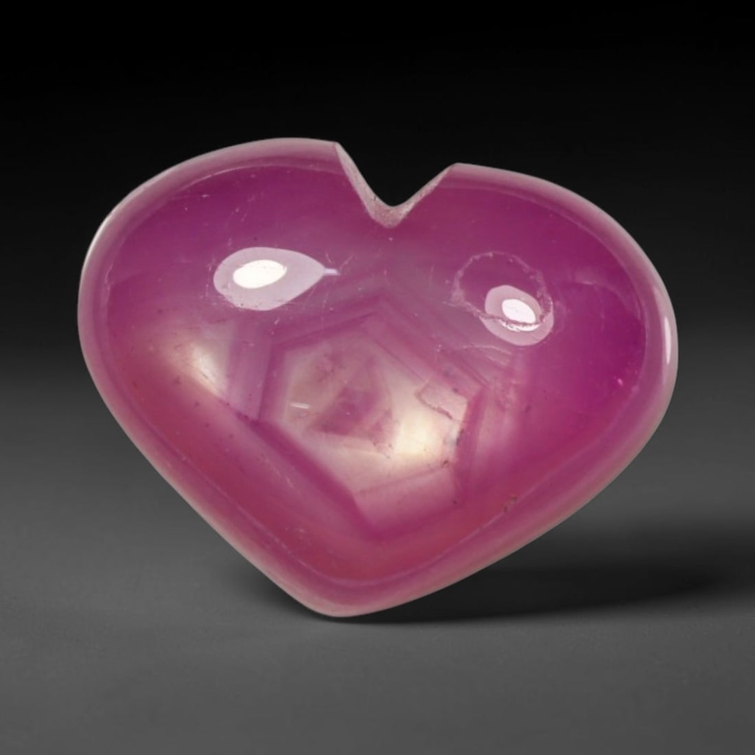 7.13ct Natural Mozambique Hot Pink Ruby Loose Gemstone, 74BP: This heart shaped Mozambique ruby cabochon measures 11.2x8.9x6.2mm, showcasing a vivid saturated hot pink body paired with stunning natural hexagonal crystal growth banding that forms a distinct geome