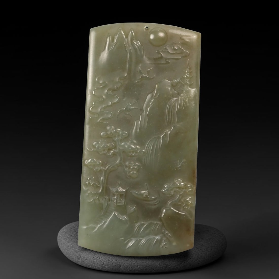 A Chinese Nephrite Jade Landscape Plaque Pendant, 81FC, 81FC: Carved from pale celadon to grey-green nephrite jade with subtle tonal variation and minor natural inclusions, the object is worked as a vertically oriented plaque with a gently curved upper edge. The