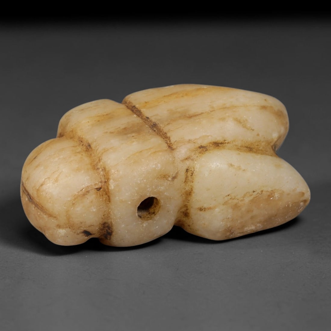 Ancient Egyptian Pale Calcite Fly Amulet (664-30 BCE), 54AB, 54AB: Simplified hand-carved pale creamy calcite talisman shaped as a fly, with shallow incised lines separating the head, thorax and wing sections. A clean drilled piercing through the midsection allows co