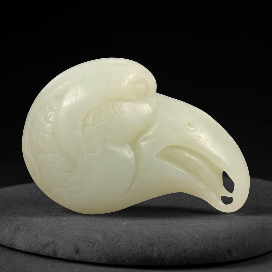 A Chinese Hetian Nephrite Jade Bird-Head Pendant, 20th Century, 30FA, 30FA: Carved from pale celadon nephrite jade with even translucency and minor natural inclusions, the object is worked in the form of a stylized bird's head shown in profile. The rounded cranial form transi