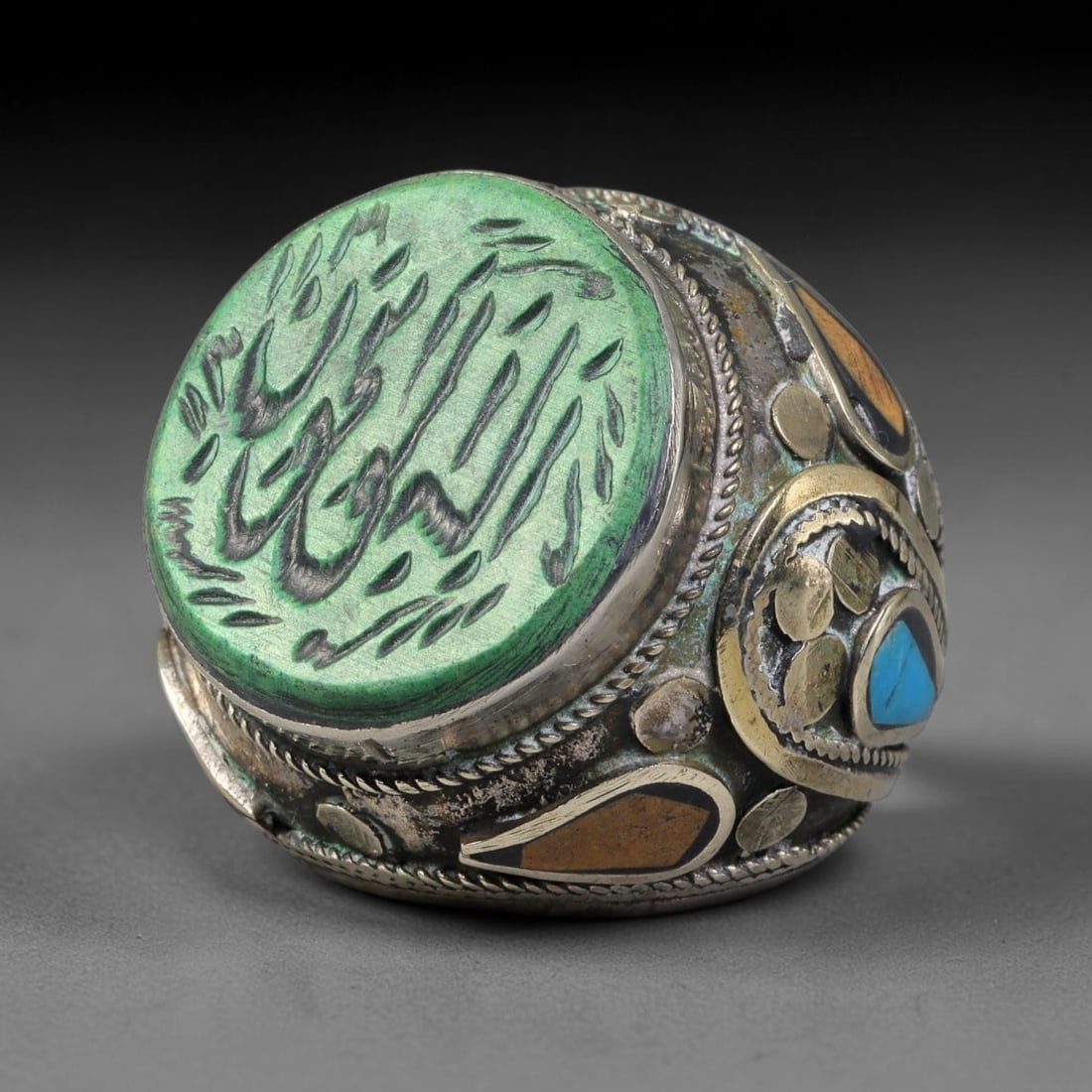 Vintage Islamic Handcrafted Silver Plated Calligraphic Talisman Statement Ring, 15BX: This vintage hand-wrought Islamic statement ring features a central engraved panel bearing traditional calligraphic detailing, set within an ornate silver-plated metal band. The mounting is enriched w