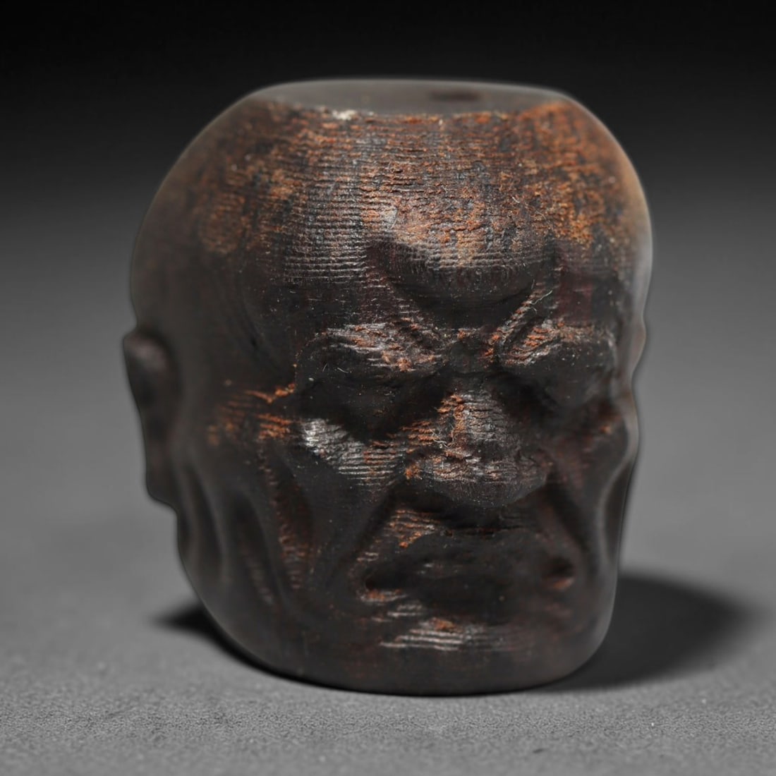 A Chinese Agar Wood Carved Head Art Bead, 35BX: Chinese agar wood head-form art bead measuring 22 x 20 mm. Detailed sculpted facial features cover the exterior surface, with a continuous central bore designed for stringing within beaded strands. Th