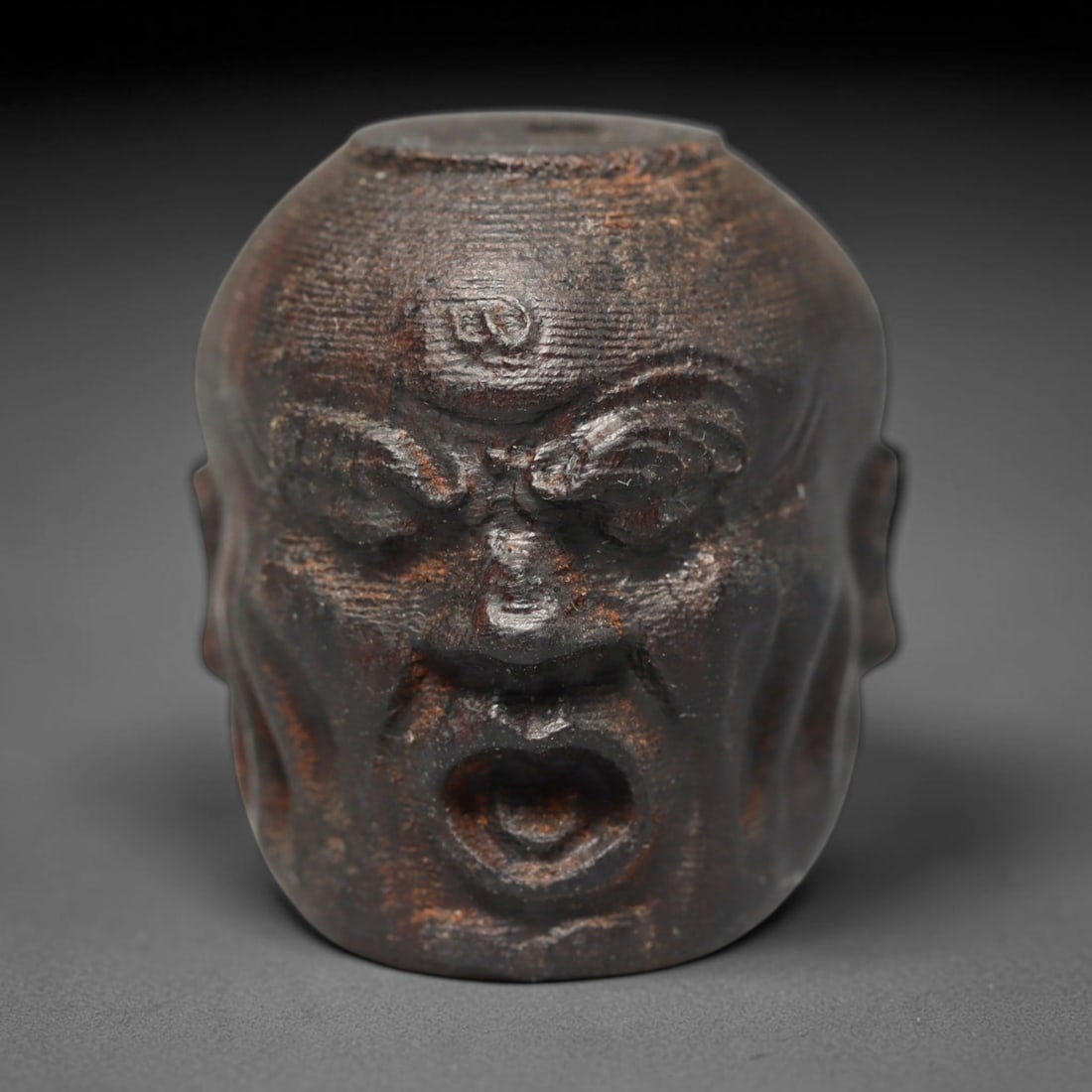 A Chinese Agar Wood Carved Head Art Bead, 27BX: Chinese agar wood head-form art bead measuring 22 x 20 mm. Detailed sculpted facial features cover the exterior surface, with a continuous central bore designed for stringing within beaded strands. Th