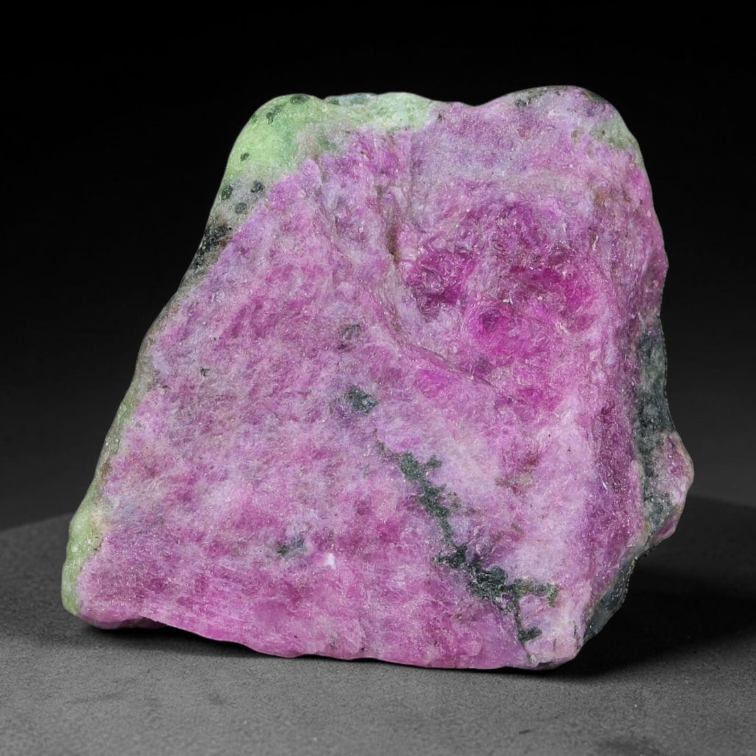 83ct Natural Tanzanian Ruby Zoisite Raw Rough Specimen Mineral Stone, 8FC: This unpolished mineral rough is natural ruby zoisite sourced from Tanzania, exhibiting distinct banded mineral segregation of vibrant green zoisite, magenta ruby crystals, and dark hornblende inclusi