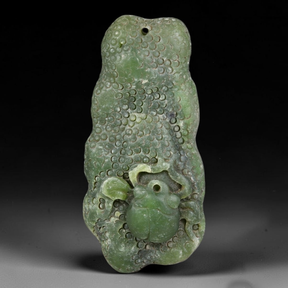 Natural Chinese Carved Green Nephrite Jade Beetle Relief Pendant, 85AT: Hand-carved natural green nephrite jade pendant with organic irregular silhouette, measuring 55 x 26 mm. The surface features dense hand-chiseled circular indent texture mimicking gnarled bark, paired
