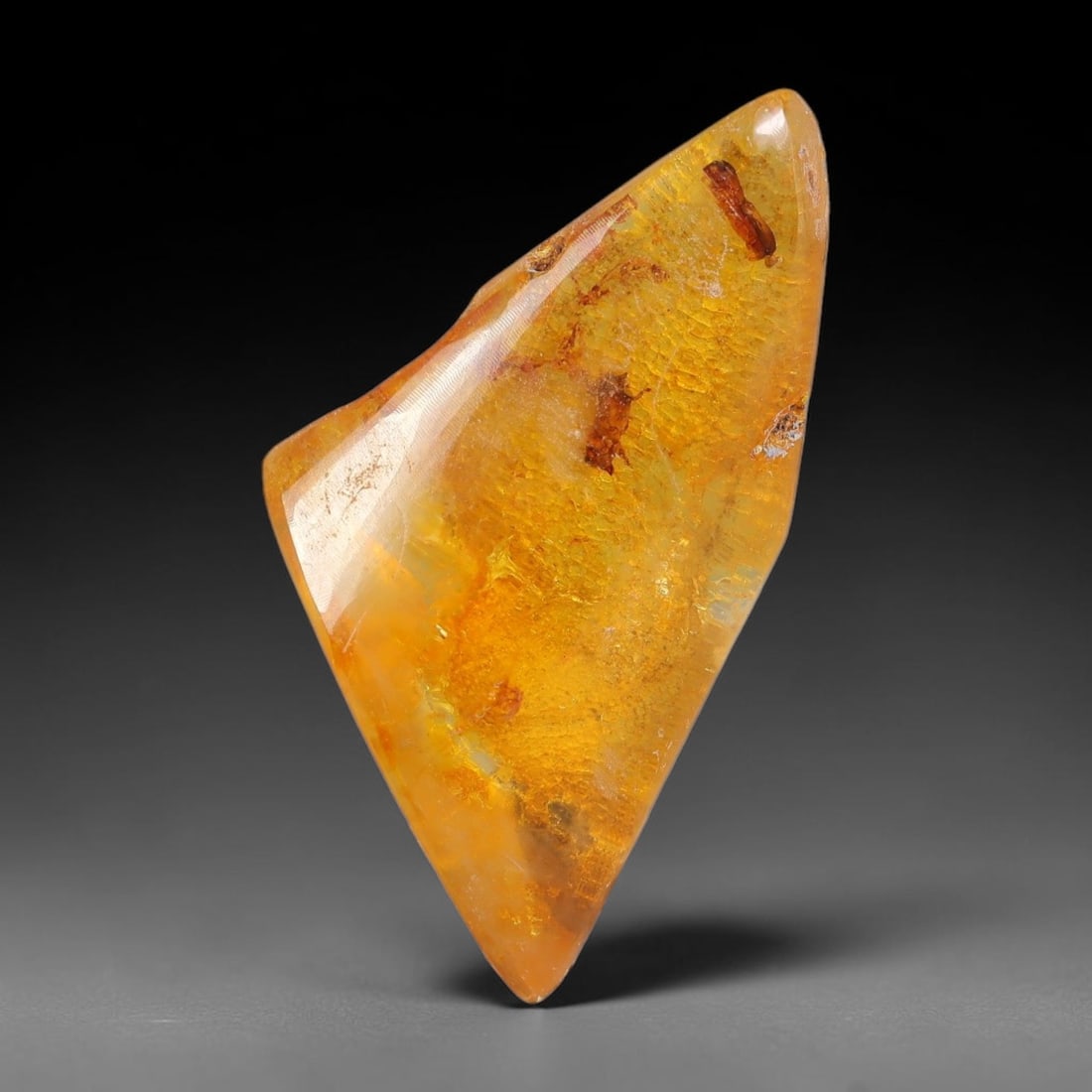 13.78ct Natural Baltic Polished Loose Freeform Amber Gemstone, 29EB: This smoothly polished freeform amber piece carries warm translucent organic clarity with fine natural fossil flecks and tiny mineral inclusions suspended throughout its 35x16mm flowing unstructured s