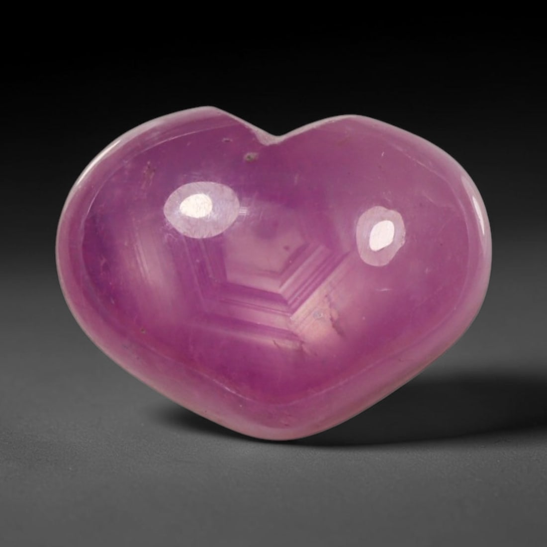 4.68ct Natural Mozambique Hot Pink Ruby Loose Gemstone, 76BP: This heart shaped Mozambique ruby cabochon measures 10.8x8.2x4.7mm, showcasing a vivid saturated hot pink body paired with stunning natural hexagonal crystal growth banding that forms a distinct geome