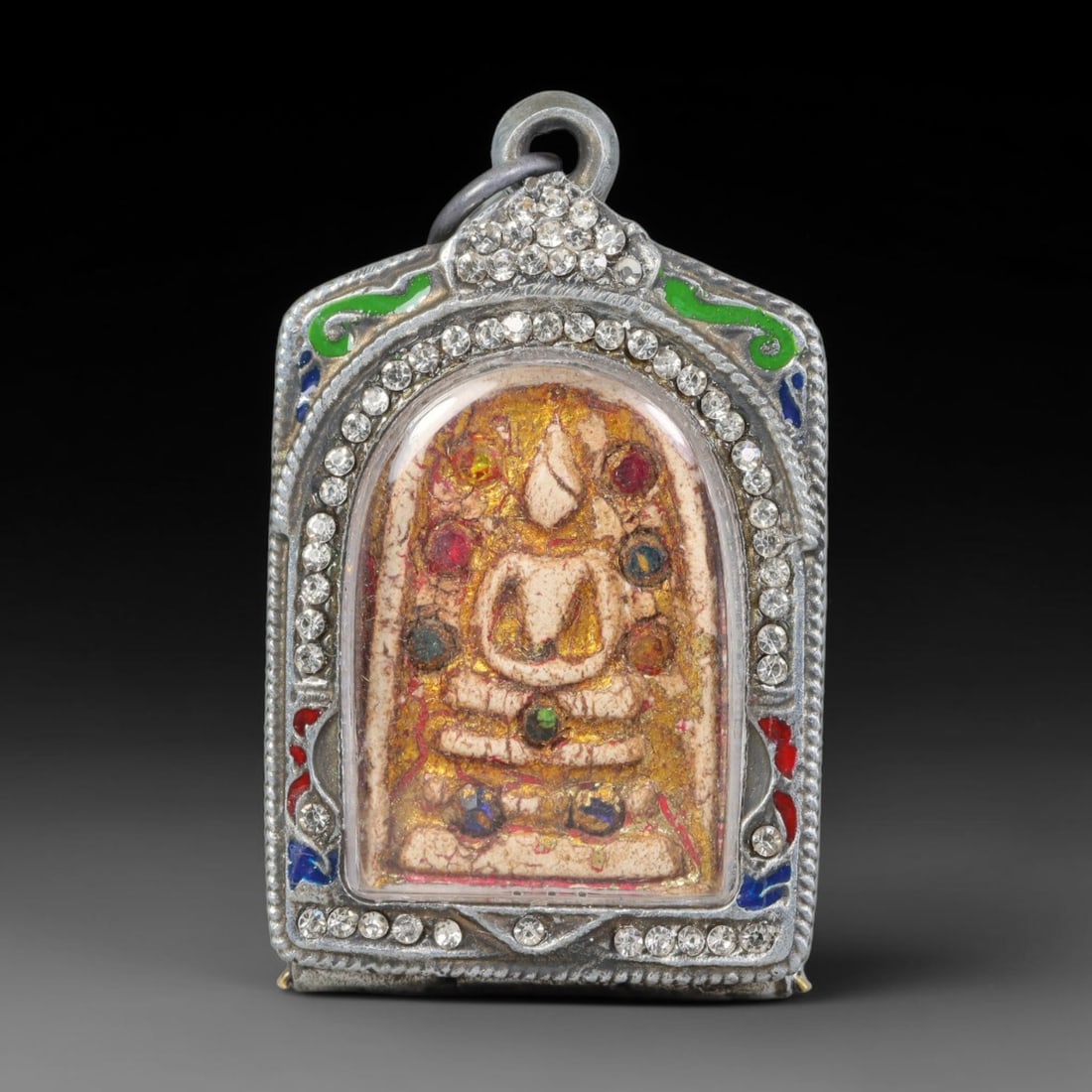 Thai Buddhist Folk Tradition Enclosed Amulet Pendant with Decorative Metal Casing, 39AH: This Thai sacred amulet is housed within an ornate hinged metal protective casing fitted with a top loop for wear as a pendant. The casing features intricate embossed surface detailing and a continuou